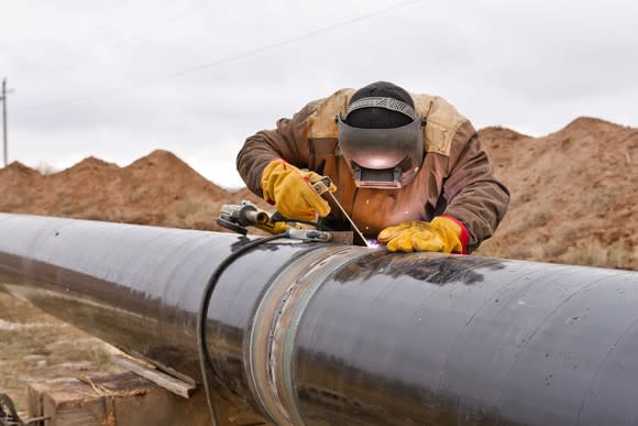 A man welding a pipe for an oil pipeline.