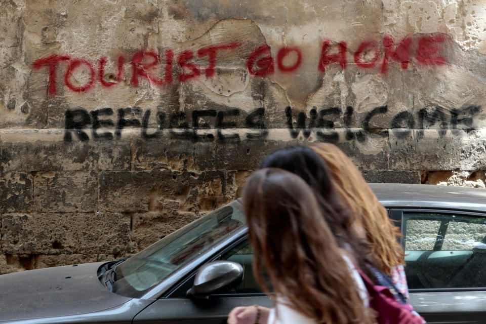 People walk past a graffiti in Palma de Mallorca, in the Spanish island of Mallorca, May 23, 2016. REUTERS/Enrique Calvo