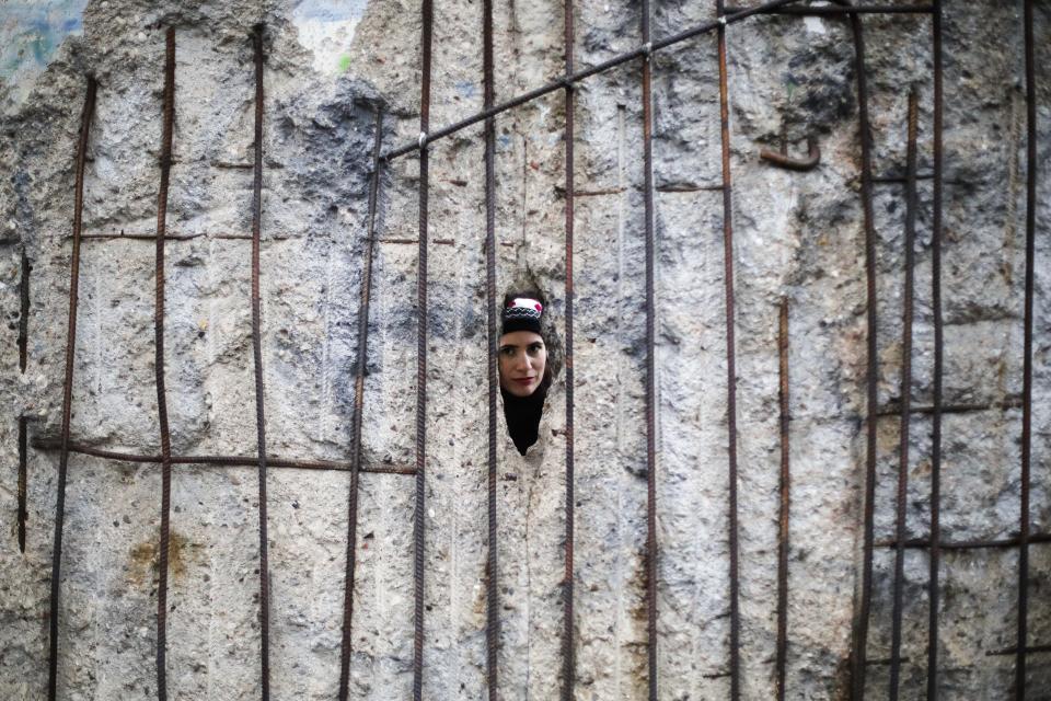 Tourist from Greece looks through the hole in remains of the Berlin Wall after commemorations celebrating the 30th anniversary of the fall of the Berlin Wall at the Wall memorial site at Bernauer Strasse in Berlin, Saturday, Nov. 9, 2019. (AP Photo/Markus Schreiber)