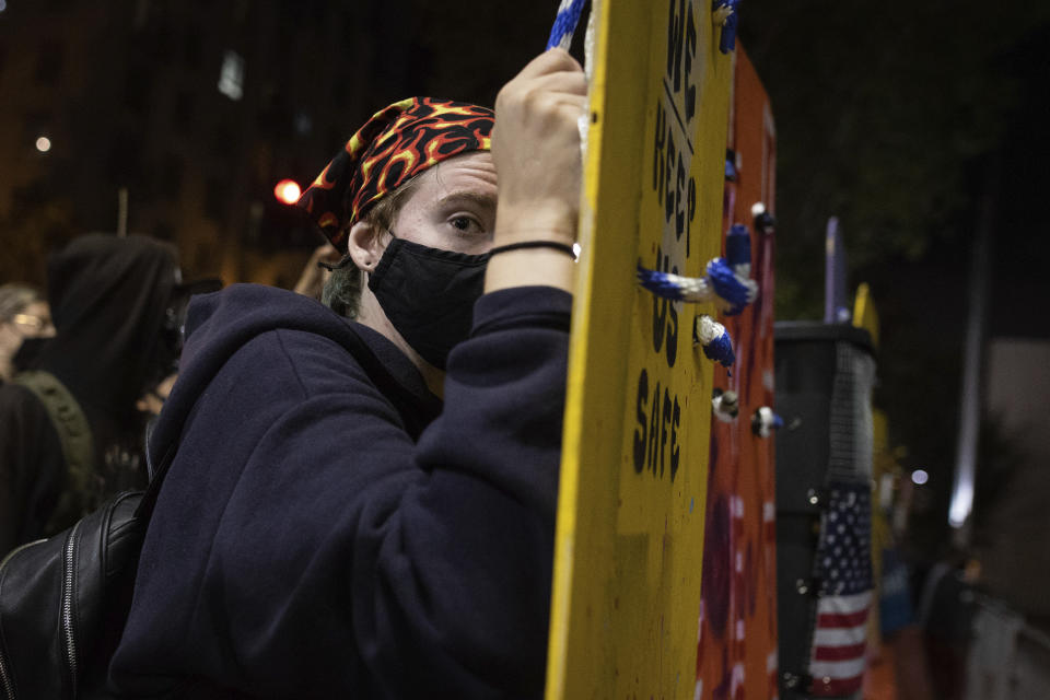 A protester holds a homemade riot shield during a protest in front of the Oakland Police Department Station on Saturday, July 25, 2020, in Oakland, Calif. Protesters in California set fire to a courthouse, damaged a police station and assaulted officers after a peaceful demonstration intensified late Saturday, Oakland police said. (AP Photo/Christian Monterrosa)