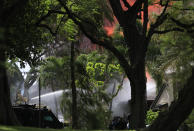 Honolulu firefighters work with police to extinguish a house fire after a shooting and domestic incident at a residence on Hibiscus Road near Diamond Head on Sunday, Jan. 19, 2020, in Honolulu. Witnesses say at least two Honolulu police officers were shot and two civilians were injured. Moments after the shooting, the house was set on fire, possibly by the suspect. (Jamm Aquino/Honolulu Star-Advertiser via AP)