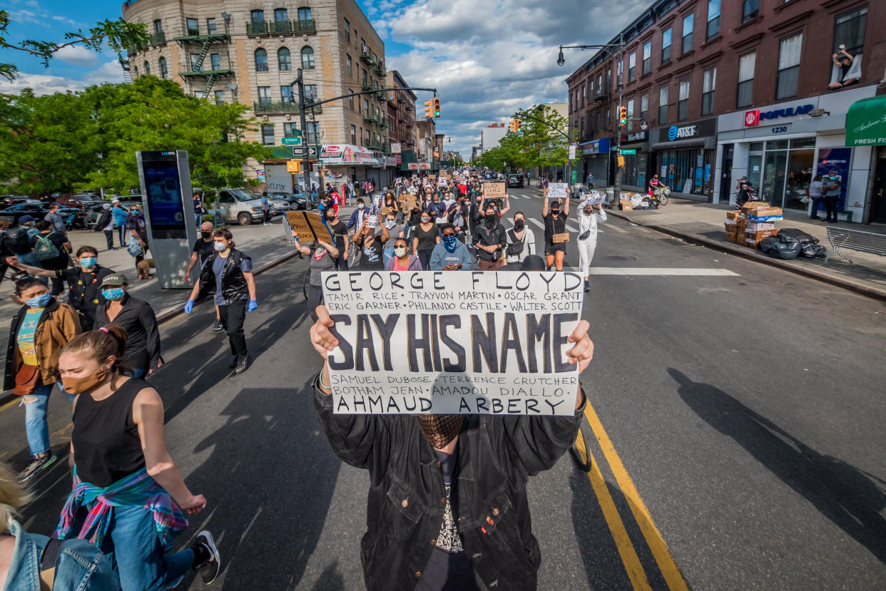 A protester holding a "Say His Name" sign in Brooklyn