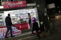 People stand in front of a "bodegon" in Caracas