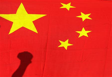 A shadow of the clenched fist of a protester is seen on a Chinese national flag during an anti-Japan protest outside the Japanese embassy in Beijing in this August 19, 2012 file photo. REUTERS/Jason Lee/Files