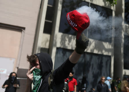 An anti-fascist protestor burns a Trump cap during the Patriots Day Free Speech Rally in Berkeley, California, U.S. April 15, 2017. REUTERS/Jim Urquhart