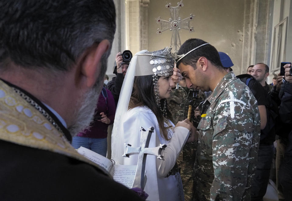 Newlyweds, soldier Hovhannes Hovsepyan, right, and Mariam Sargsyan get married in the Holy Savior Cathedral, damaged by shelling by Azerbaijan's artillery during a military conflict in Shushi, the separatist region of Nagorno-Karabakh, Saturday, Oct. 24, 2020. The wedding was celebrated even as intense fighting in the region has continued. (AP Photo)