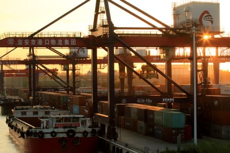 FILE PHOTO: Cargo ship is seen next to containers at a river port during sunset in Huaian