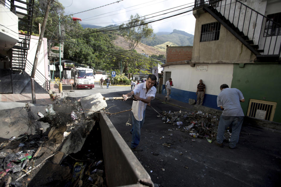 Cotiza neighborhood residents clean up a day after isolated protests in response to the arrest of National Guardsmen who mounted an uprising against President Nicolas Maduro, in Caracas, Venezuela, Tuesday, Jan. 22, 2019. Working class neighborhoods in Venezuela's capital sifted through charred rubble and smoldering trash on Tuesday, after violence erupted in the streets a day prior. (AP Photo/Fernando Llano)