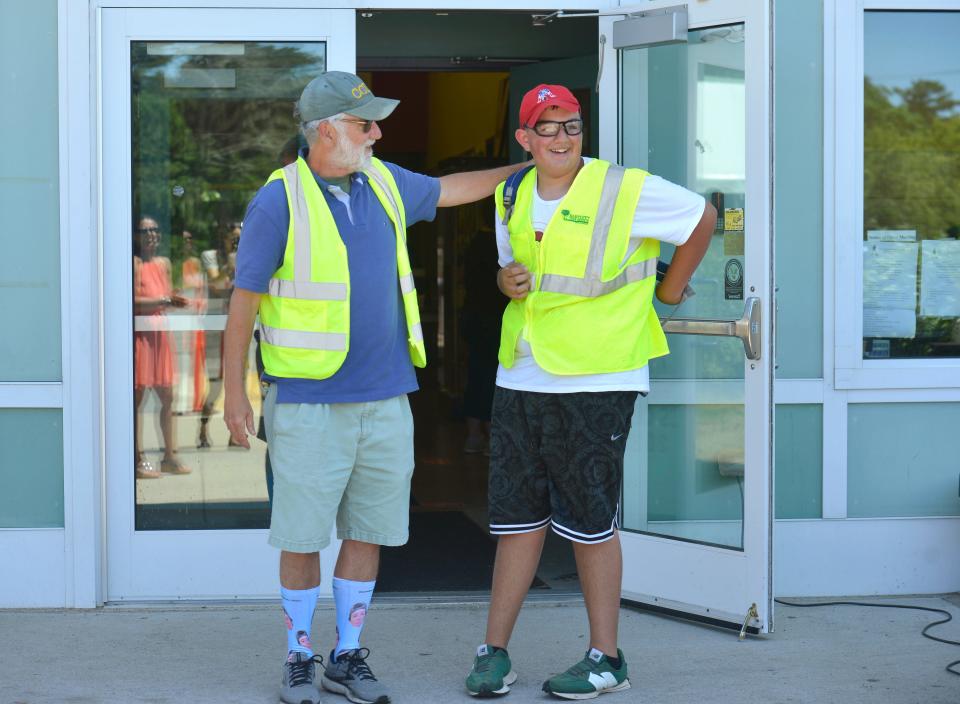 Seventh grader John "JR" Cummings, of South Yarmouth, right, wears a reflective safety vest to look like Cape Cod Lighthouse Charter School Executive Director Paul Niles who wears a similar vest when he directs buses and parent pickups.  Niles is retiring, and Tuesday was the last time he waved goodbye to students as they left the Harwich school.