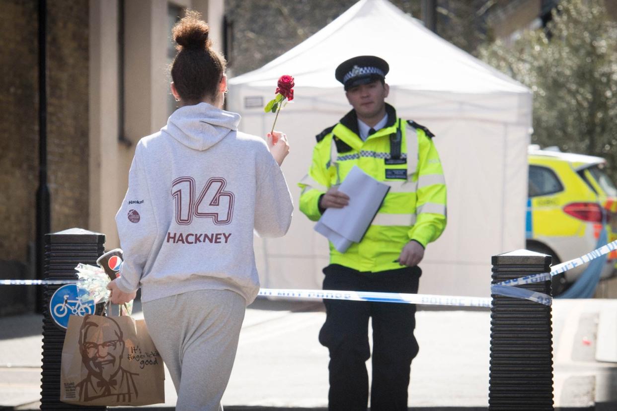 A friend leaves a tribute at the scene of a murder in Hackney: Stefan Rousseau/PA