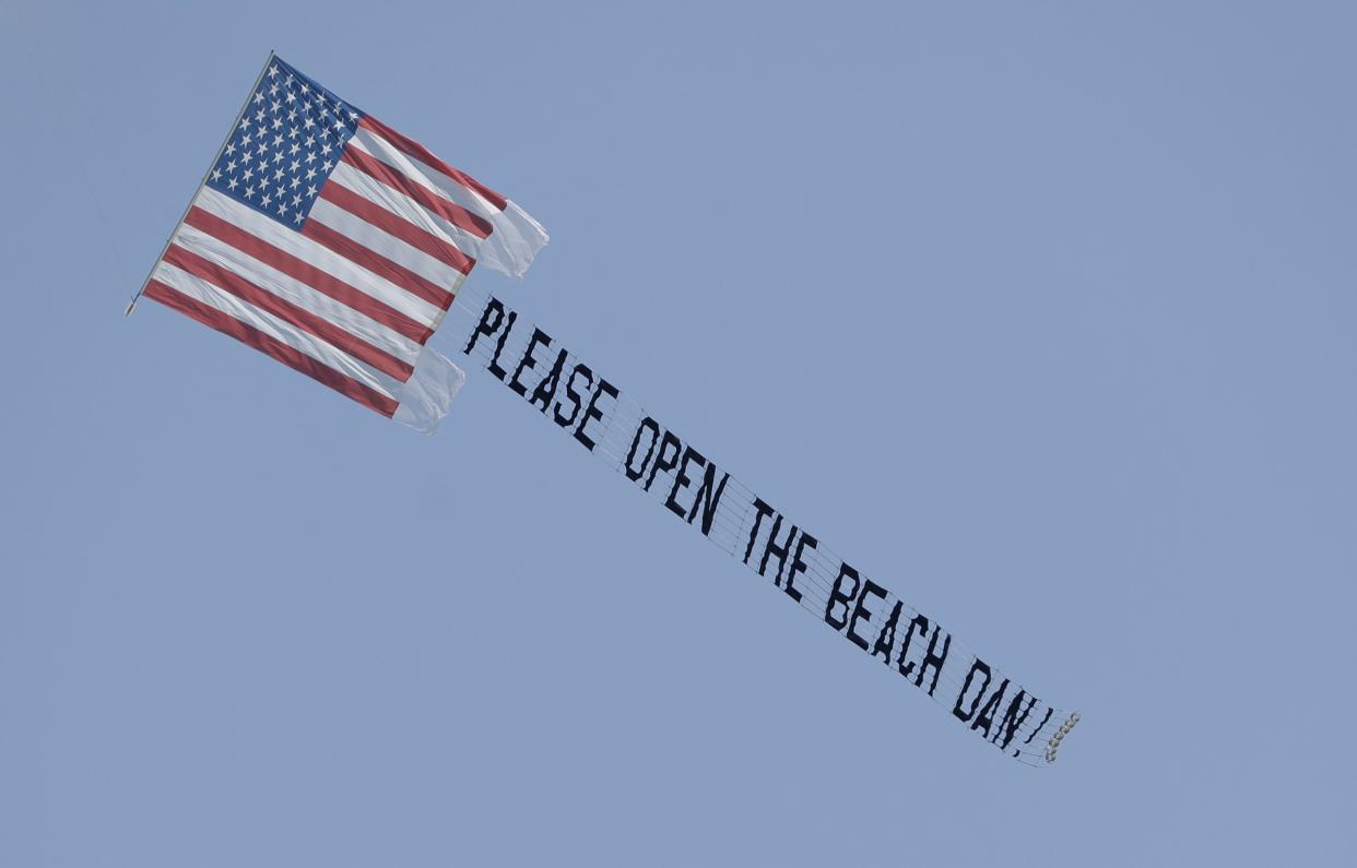 A banner plane flies a sign urging Miami Beach, Fla. Mayor Dan Gelber to open the beaches, which have been closed due to the coronavirus outbreak on Sunday, April 19, 2020, in Miami Beach, Fla.