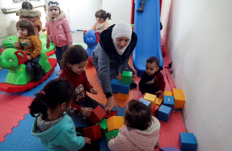 Safaa Kamel, a teacher, plays with children at a school in the northern Syrian town of Afrin