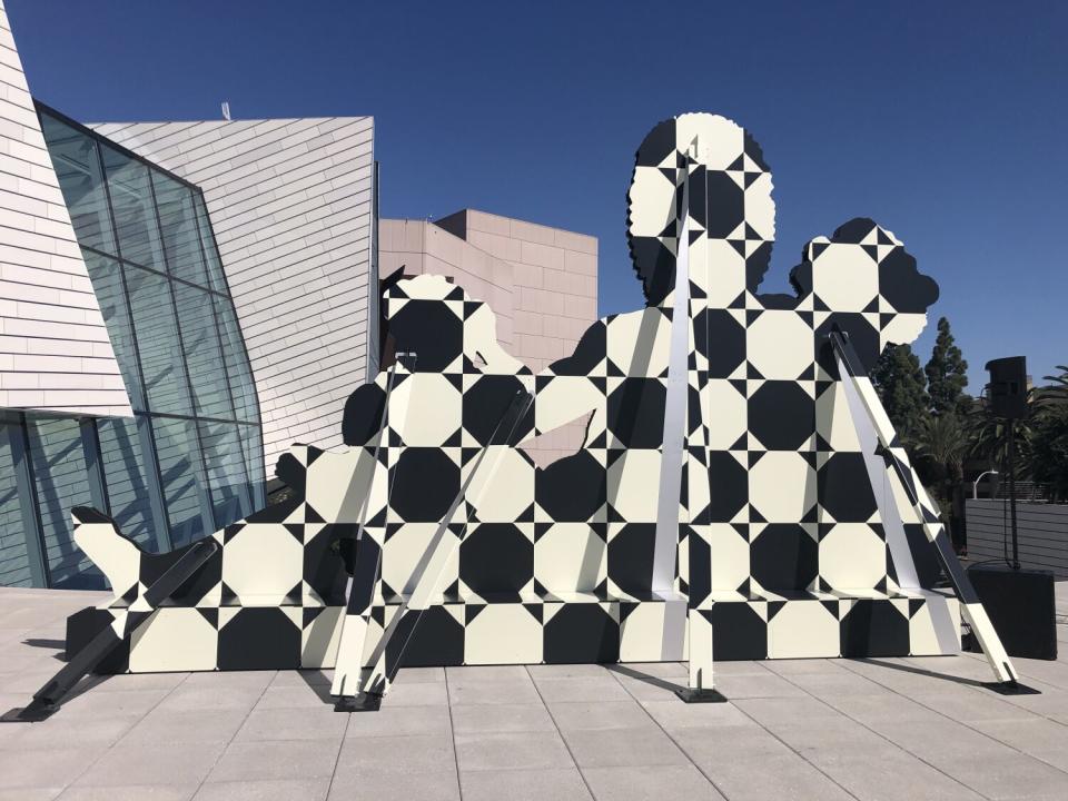 The outline of a human figure is rendered in a black and white geometric pattern on aluminum, supported by a scaffold.