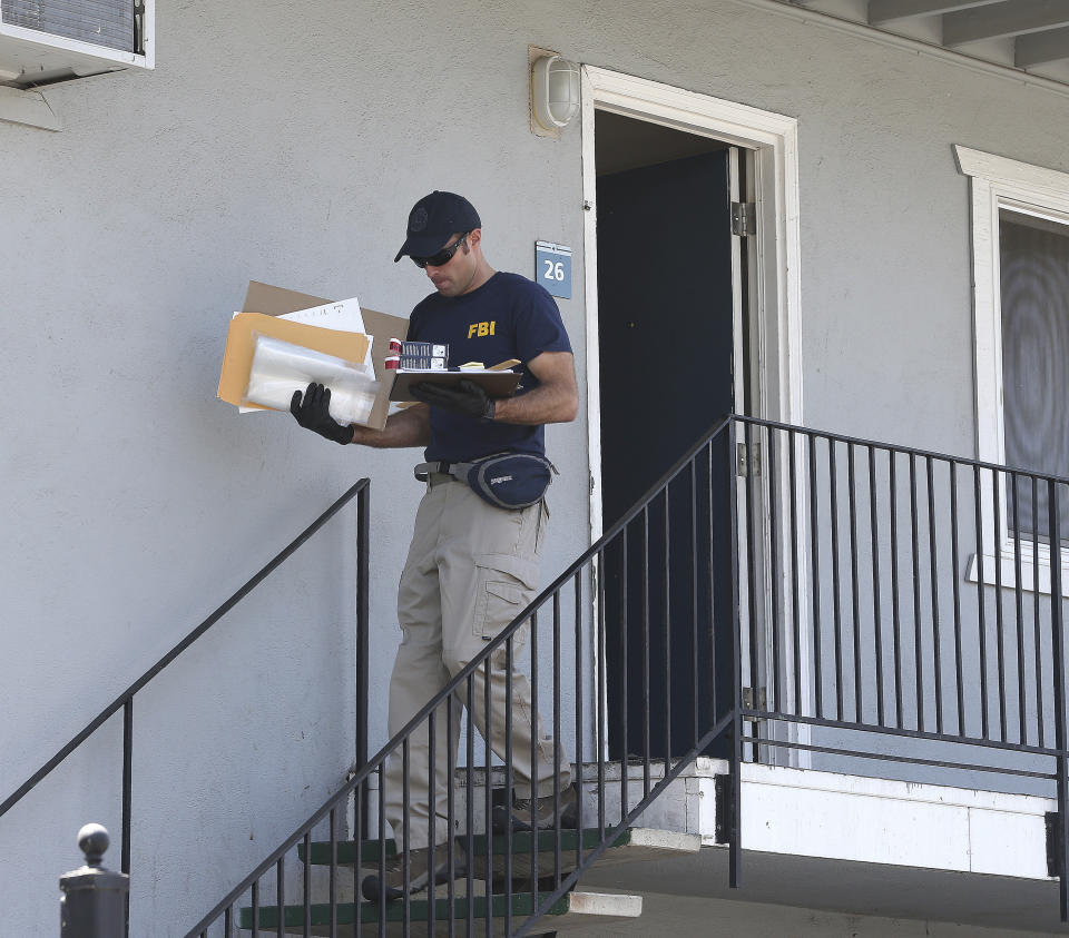 A federal agent removes items from an apartment following the arrest of a 45-year-old Iraqi refugee, Omar Ameen, Wednesday, Aug. 15, 2018, in Sacramento, Calif. Ameen was arrested on a warrant alleging that he killed an Iraqi policeman in 2014 while serving with the Islamic State terror organization. (AP Photo/Rich Pedroncelli)