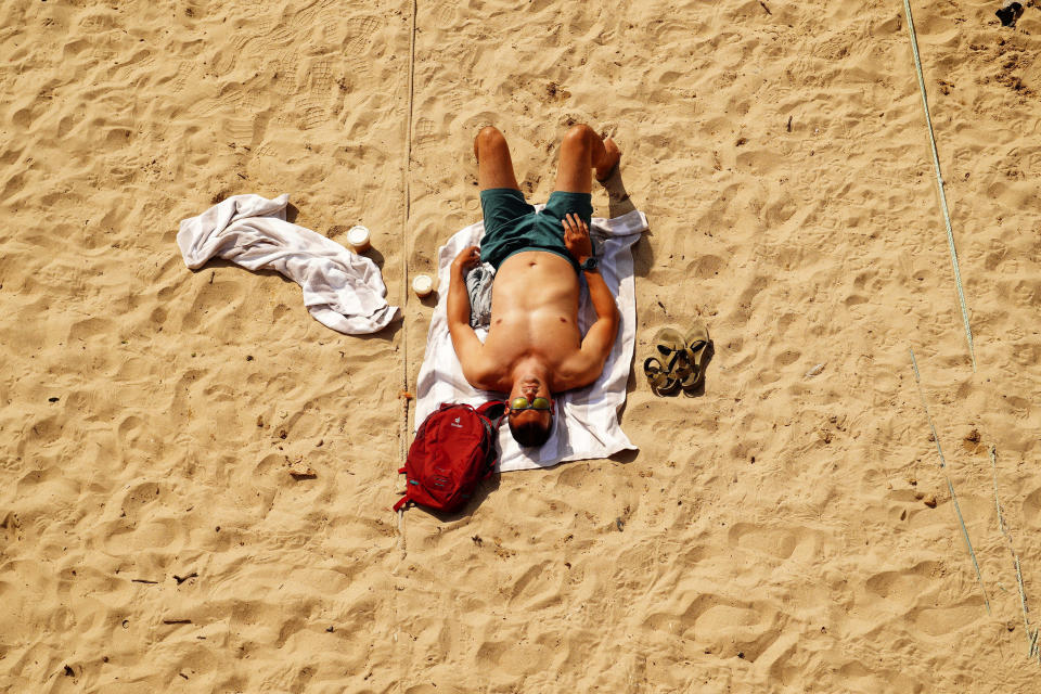 A man sunbathes on the beach at Mousehole, Cornwall, in England, Monday, July 18, 2022. Britain’s first-ever extreme heat warning is in effect for large parts of England as authorities prepare for record high temperatures that are already disrupting travel, health care and schools. The “red” alert will last throughout Monday and Tuesday when temperatures may reach 40 degrees Celsius (104 Fahrenheit) for the first time, posing a risk of serious illness and even death among healthy people, according to the U.K. Met Office, the country’s weather service. (Ben Birchall/PA via AP)