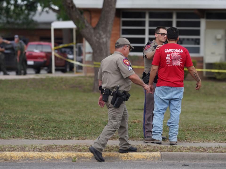 Law enforcement officers speak to a man outside of Robb Elementary School in Uvalde, Texas, on May 24, 2022