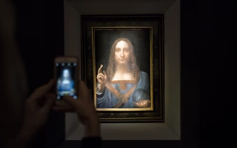 A visitor takes a photo of the painting 'Salvator Mundi' by Leonardo da Vinci at Christie's New York Auction House, November 15, 2017 in New York City. - Credit: Drew Angerer/Getty Images North America