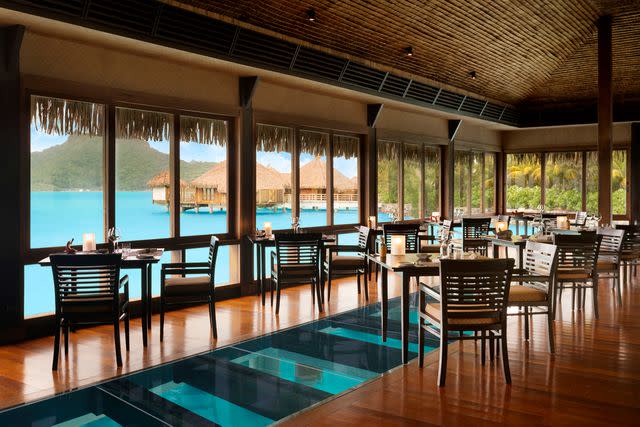 <p>Courtesy of The St. Regis Bora Bora</p> Inside the haute The Lagoon Restaurant, diners can glimpse marine life swimming below their table.