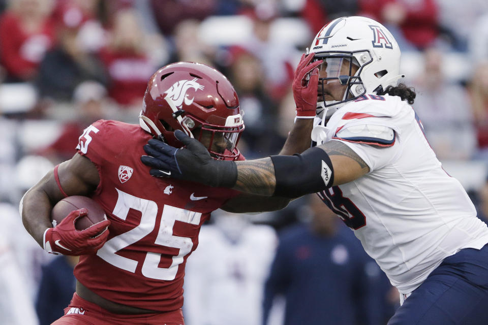 Washington State running back Nakia Watson (25) carries the ball while pressured by Arizona defensive lineman Tiaoalii Savea during the first half of an NCAA college football game Saturday, Oct. 14, 2023, in Pullman, Wash. (AP Photo/Young Kwak)