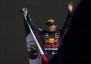 Red Bull's Sergio Perez holds a Mexican flag as he celebrates winning third place of the Formula One Mexico Grand Prix auto race at the Hermanos Rodriguez racetrack in Mexico City, Sunday, Nov. 7, 2021. (AP Photo/Fernando Llano)
