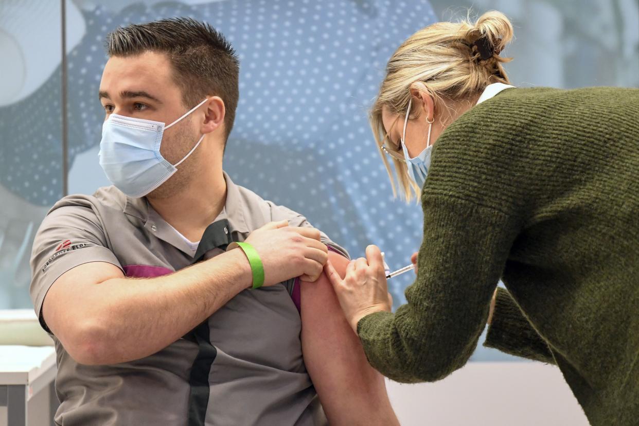 A healthcare worker, left, is administered a shot of the Pfizer-BioNTech coronavirus vaccine at a mass vaccination center in Veghel, Netherlands, Wednesday, Jan. 6, 2021. Nearly two weeks after most other European Union nations, the Netherlands on Wednesday began its COVID-19 vaccination program, with care home staff and frontline workers in hospitals first in line for the shot.
