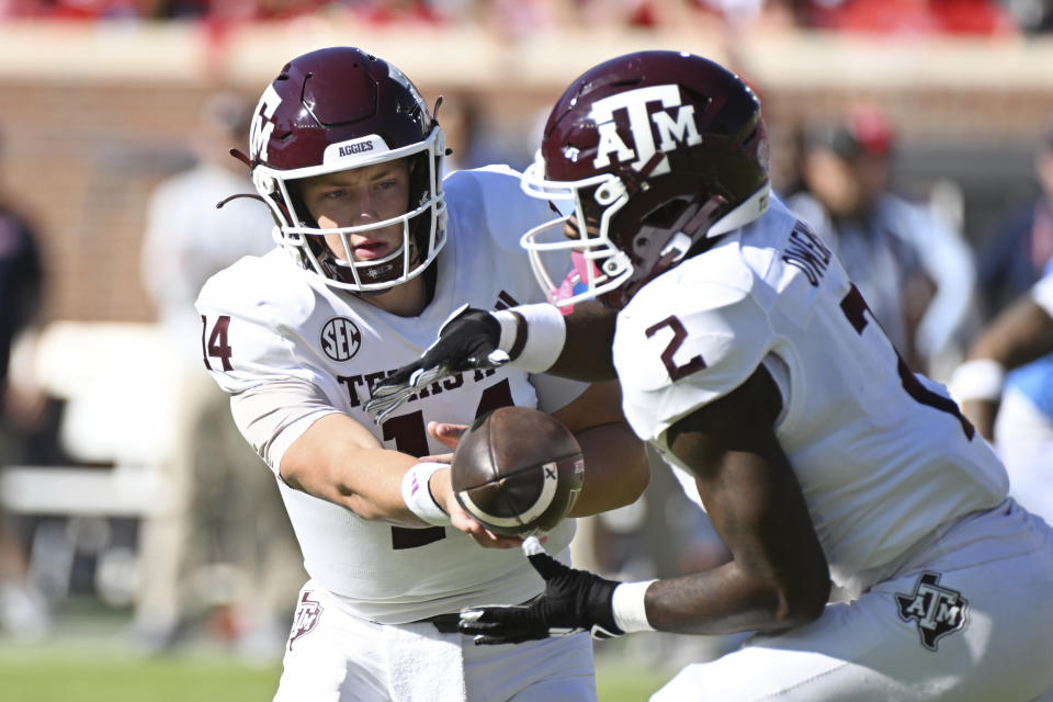 Texas A&M quarterback Max Johnson (14) hands the ball off to running back Rueben Owens (2) during the first half of an NCAA college football game against Mississippi in Oxford, Miss., Saturday, Nov. 4, 2023. (AP Photo/Thomas Graning)