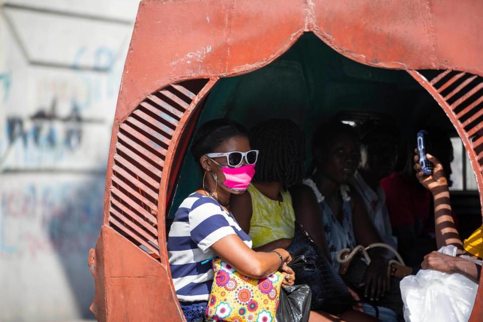 People sit in a Tap-tap while a passenger wears a mask to protect herself from the spread of the new coronavirus in Port-au-Prince, Haiti. Fear of insecurity has ridership on public buses down, transport unions say.