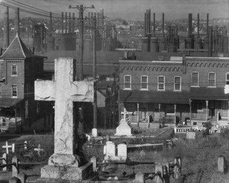 A cross stands in a cemetry, while factories are seen in the distance in this handout out photograph Bethlehem, November 1935. Walker Evans/U.S. Farm Security Administration/Library of Congress via REUTERS