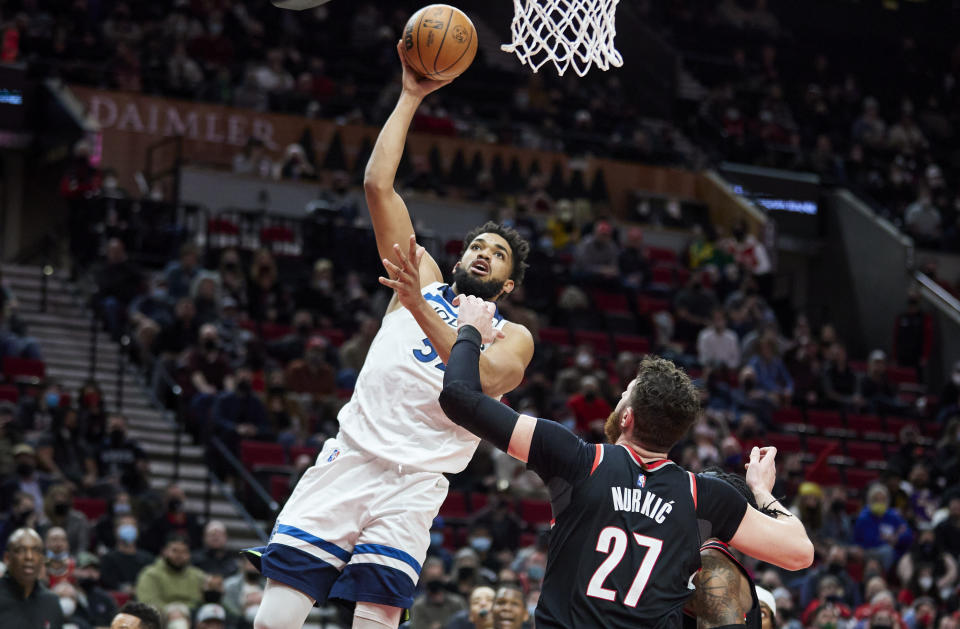 Minnesota Timberwolves center Karl-Anthony Towns, left, shoots over Portland Trail Blazers center Jusuf Nurkic during the second half of an NBA basketball game in Portland, Ore., Tuesday, Jan. 25, 2022. (AP Photo/Craig Mitchelldyer)