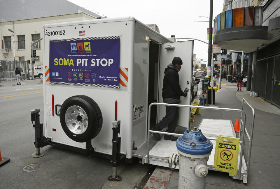 An attendant exits a "Pit Stop" public toilet on Sixth Street, Thursday, Aug. 1, 2019, in San Francisco. A 5-year-old portable toilet program in San Francisco that provides homeless people with a private place to go has expanded to 25 locations in the city and has spread to Los Angeles. Not everyone who uses the “Pit Stop” toilets is homeless, but advocates say steam cleaning requests have dropped in surrounding areas. (AP Photo/Eric Risberg)