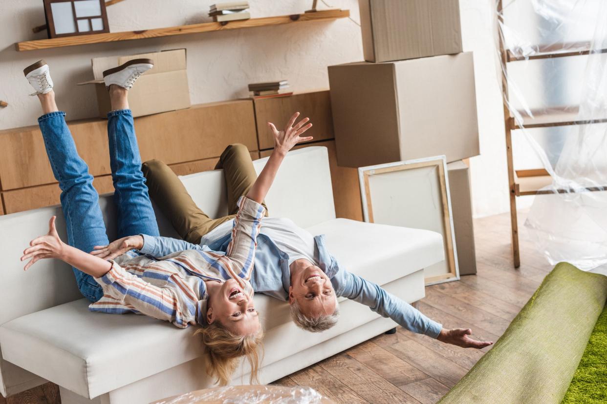 excited mature couple lying on couch during relocation in new house stock
