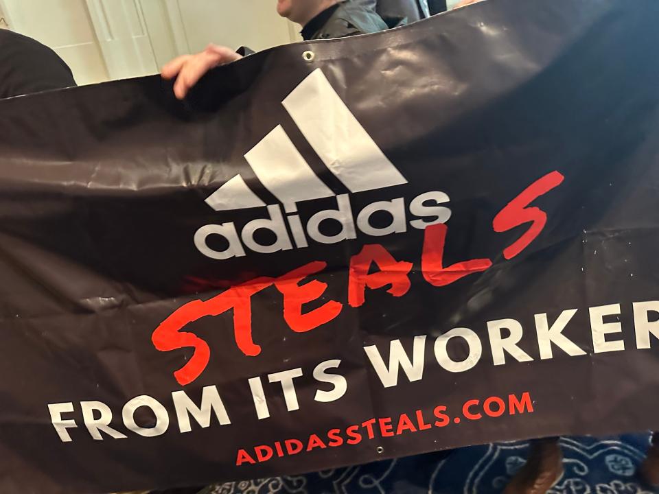 Protestors unfurled a banner that demanded Adidas reimburse allegedly unpaid wages of contract factory workers.