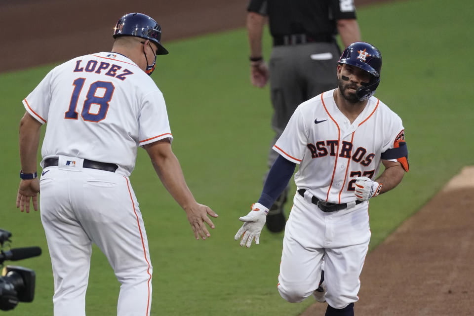Houston Astros' Jose Altuve is congratulated by third base coach Omar Lopez after hitting a solo home run against against the Tampa Bay Rays starting pitcher Ryan Yarbrough during the first inning in Game 3 of a baseball American League Championship Series, Tuesday, Oct. 13, 2020, in San Diego. (AP Photo/Ashley Landis)