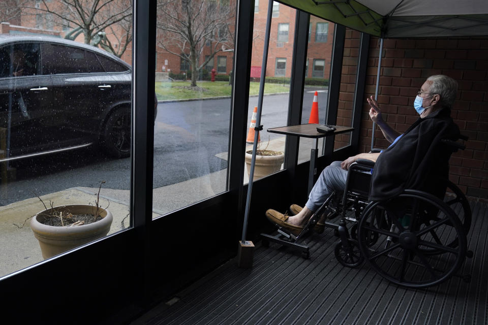 John O'Malley, right, visits with his son during a drive-by visit at The Hebrew Home at Riverdale in New York, Wednesday, Dec. 9, 2020. New dog recruits are helping to expand the nursing home's pet therapy program, giving residents and staff physical comfort while human visitors are still restricted because of the pandemic. (AP Photo/Seth Wenig)