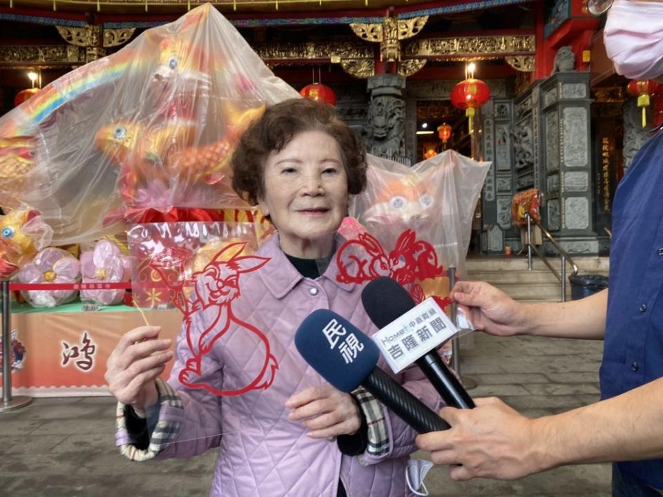 基隆四大古寺慈雲寺臘月十五邀請名家揮毫免費送春聯，慈雲寺主委李林寶玉手持紅紙窗花喜氣洋洋。(記者王慕慈攝)