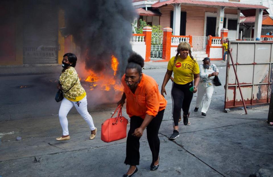 People run past a burning barricade during a demonstration demanding the resignation of President Jovenel Moïse, in Port-au-Prince, Haiti, Friday, Jan. 15, 2021.