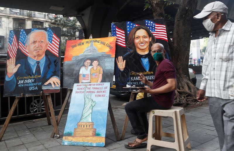 A man walks past paintings of U.S. President-elect Joe Biden and Vice President-elect Kamala Harris in Mumbai