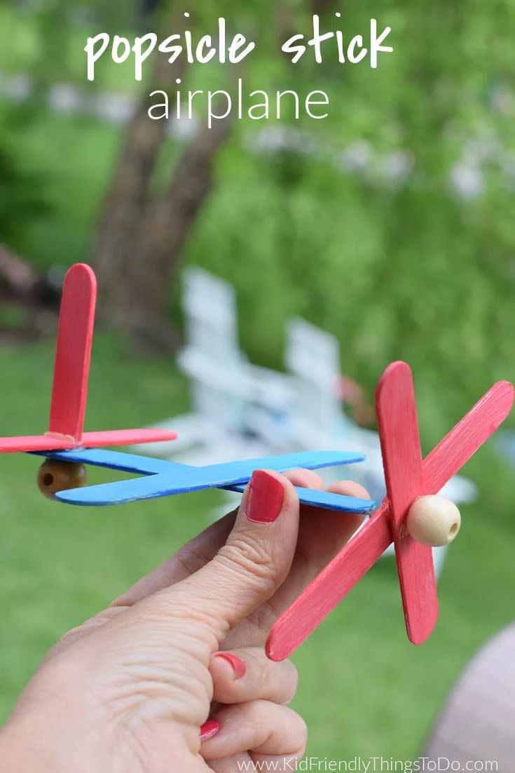 crafts for kids, hand holding a craft stick airplane outdoors