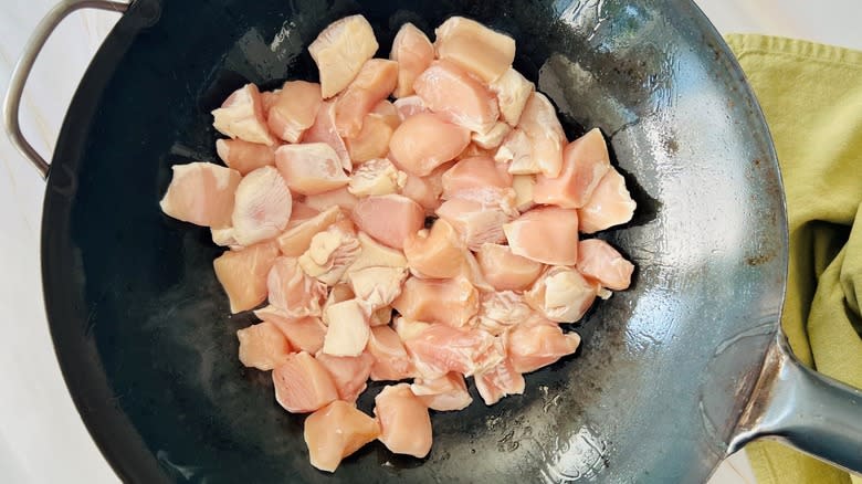 raw chicken pieces in wok