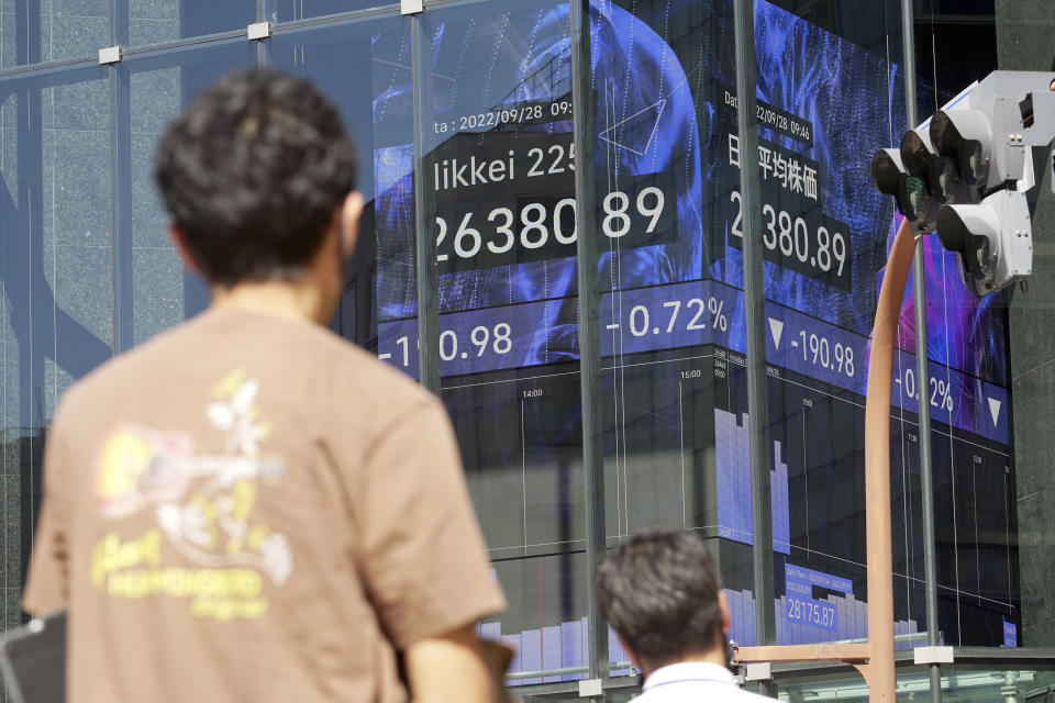 Pedestrians stand in front of an electronic stock board showing Japan's Nikkei 225 index at a securities firm Wednesday, Sept. 28, 2022, in Tokyo. Asian shares tumbled Wednesday after a wobbly day ended with mixed results on Wall Street as markets churn over the prospect of a possible recession. (AP Photo/Eugene Hoshiko)