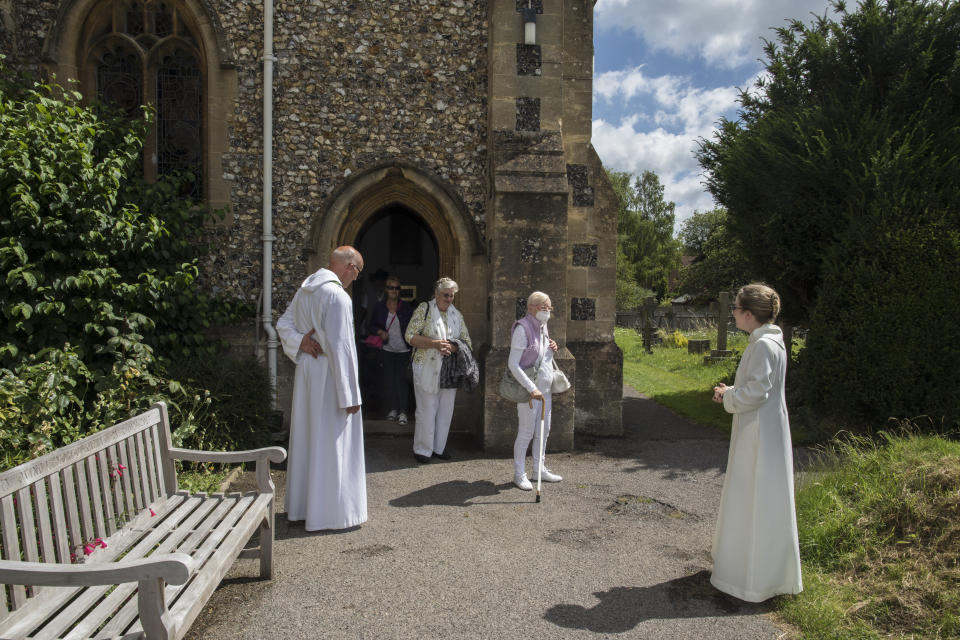 The Rev. Jonathan Gordon, left, and Assistant Vicar Miranda Sheldon, right, greet Anglican worshippers who attended their first communal prayer service after pandemic restrictions were eased, at St. Mary's Church, Northchurch in Berkhamsted, England, on Sunday, July 5, 2020. On March 24, the Church of England closed all its buildings. "It posed an immediate and immense challenge," Gordon says. "It meant that we had to completely rethink how we did everything." (AP Photo/Elizabeth Dalziel)