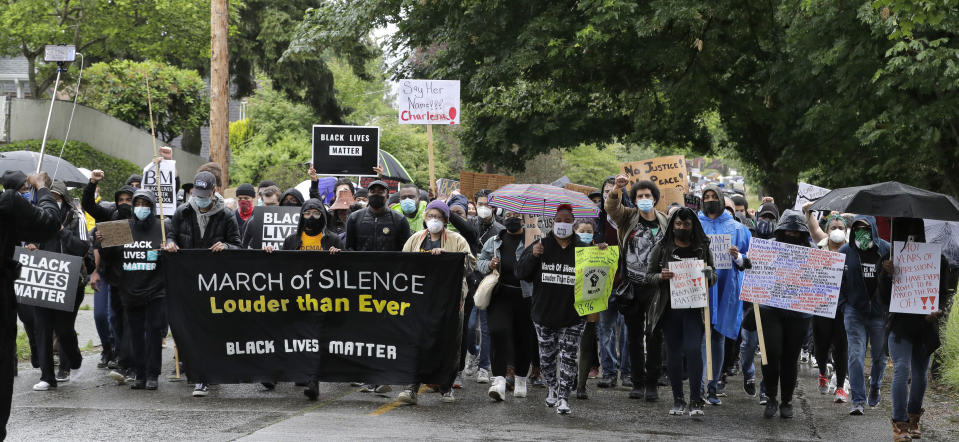 Protesters raise their fists and carry signs as they take part in a "Silent March" against racial inequality and police brutality that was organized by Black Lives Matter Seattle-King County, Friday, June 12, 2020, in Seattle. People marched for nearly two miles to support Black lives, oppose racism and to call for police reforms among other issues. (AP Photo/Ted S. Warren)