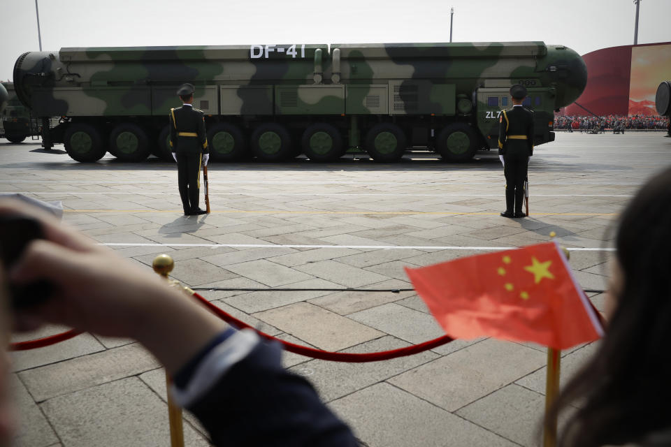 Spectators wave Chinese flags as military vehicles carrying DF-41 ballistic missiles roll during a parade to commemorate the 70th anniversary of the founding of Communist China in Beijing, Tuesday, Oct. 1, 2019. China on Friday, Jan. 21, 2022, criticized Washington for imposing sanctions on Chinese companies the U.S. says exported missile technology and accused the United States of hypocrisy for selling nuclear-capable cruise missiles. (AP Photo/Mark Schiefelbein)