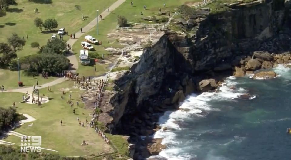 Paramedics seen at the Sydney cliff where the 20-year-old fell.