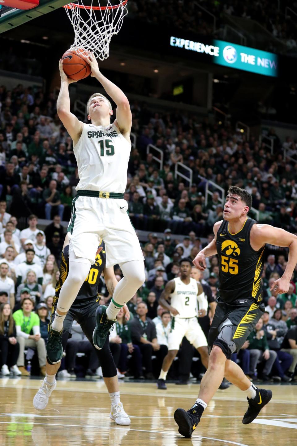 Michigan State Spartans forward Thomas Kithier (15) scores against Iowa Hawkeyes center Luka Garza (55) during first half action Tuesday, February 25, 2020 at the Breslin Center in East Lansing, Mich.