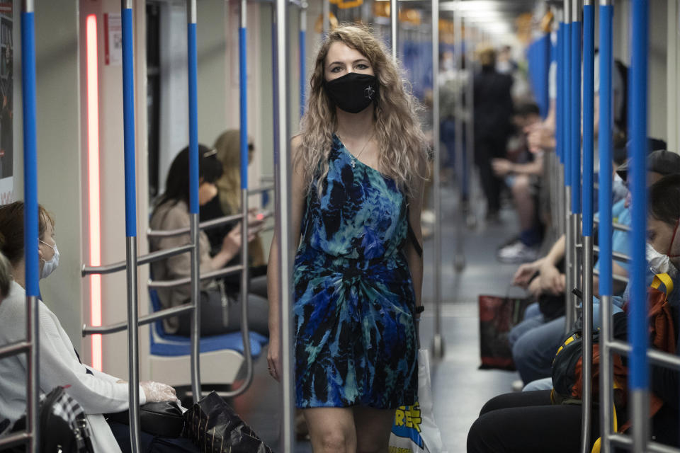 A woman wearing a face mask to protect against coronavirus walks in a carriage of a subway in Moscow, Russia, Wednesday, June 10, 2020. Moscow residents are no longer required to stay at home or obtain electronic passes for traveling around the city. All restrictions on taking walks, using public transportation or driving have been lifted as well. (AP Photo/Pavel Golovkin)