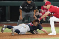 Cleveland Guardians' Will Brennan (63) dives back to first base and is hit with a pickoff throw to Texas Rangers first baseman Nathaniel Lowe, right, as umpire Erich Bacchus looks on during the ninth inning of a baseball game in Arlington, Texas, Friday, Sept. 23, 2022. (AP Photo/LM Otero)