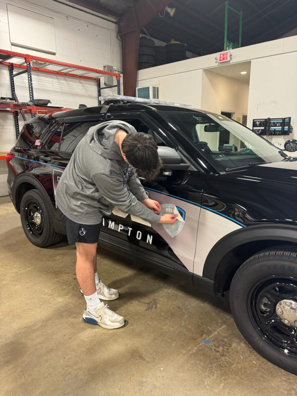 WHS senior Kaleb Joiner adds the finishing touch — the North Hampton Police Department’s emblem — to the innovative cruiser design he crafted alongside classmate Cloe Marx