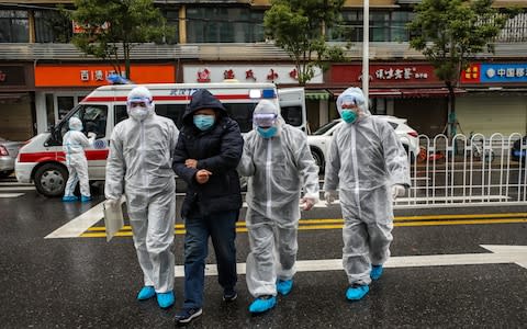  Medical staff help a patient walk into the hospital in Wuhan  - Credit: Barcroft Media