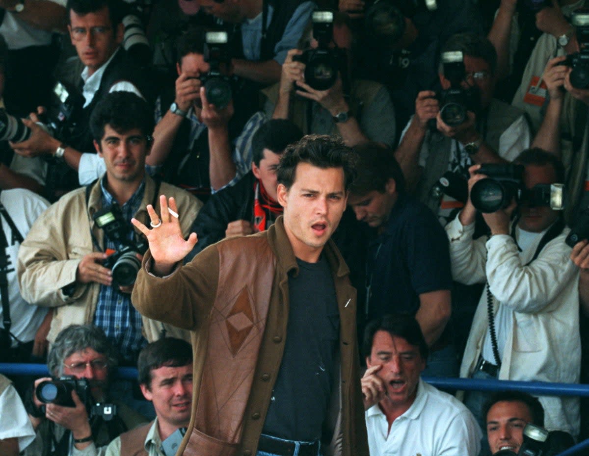Johnny Depp waves to end a photo call for director Jim Jarmusch’s film ‘Dead Man’ at the 48th Cannes on 27 May 1995 (Reuters)